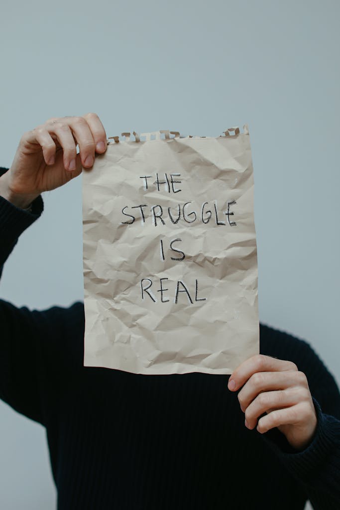 A person holding a creased paper with the text 'The struggle is real.'