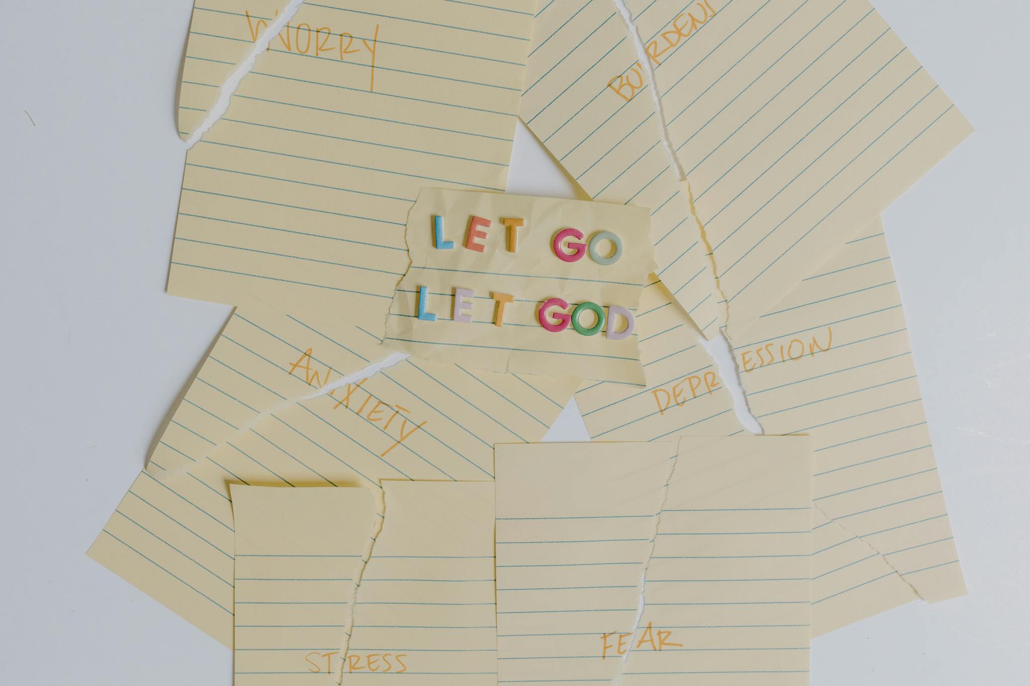 Flat lay of torn notes with an inspirational 'Let Go, Let God' message.